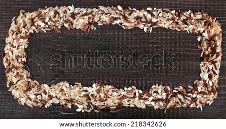 Frame made of colorful blend of several varieties of whole grain rice in a rustic wooden surface background