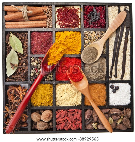 Assortment of powder spices on spoons in wooden box isolated on a white background