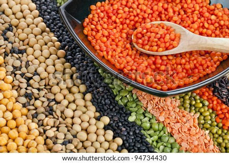 colorful striped rows of dry lentils, grain ,peas, groats , soybeans, legumes, rice, backdrop with  plate dish