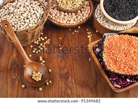Different kinds of bean seeds, lentil, peas in dish on wooden desk
