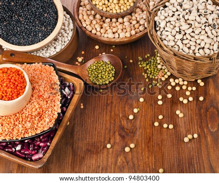 Different kinds of bean seeds, lentil, peas in dish on wooden desk
