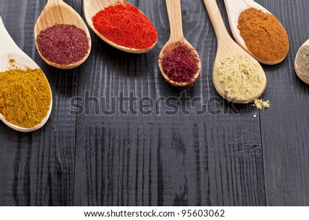 Powder spices in  wooden spoons on black desk background