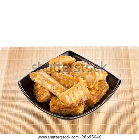 fried tofu, soy products on black plate bowl isolated on white background