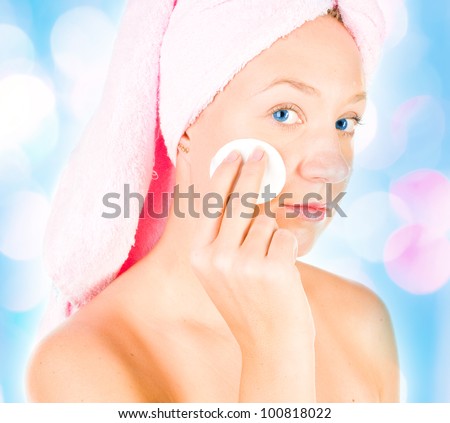 Beautiful young woman removing cosmetics with cleansing pad