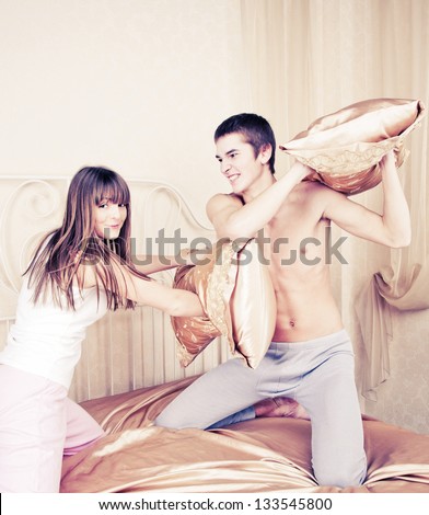 Young couple fighting pillows in the bedroom