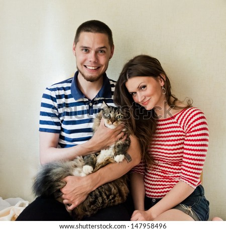 happy young couple at home with their cat