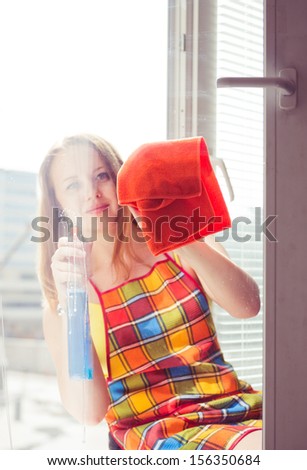 happy young woman housewife washes a window
