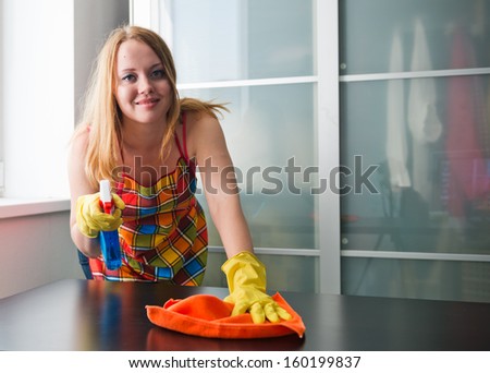 Happy girl cleaning table with furniture polish at home