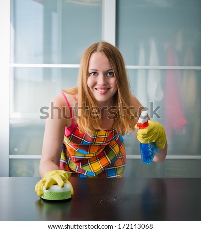 Happy girl cleaning table with furniture polish at home