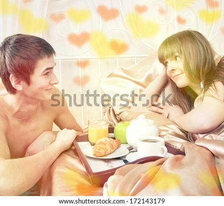 Valentine\'s day concept. Happy man and woman having luxury hotel breakfast in bed together