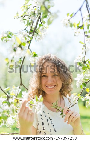 beautiful young brunette woman standing near the apple tree on a warm summer day