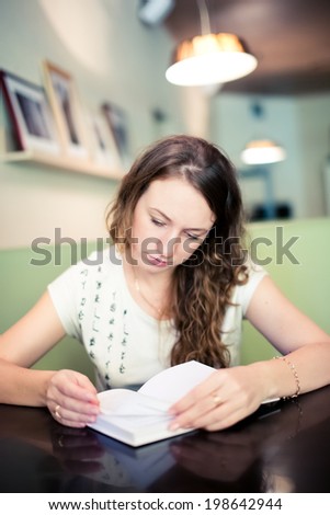 Lady reads an interesting book sitting at the cafe