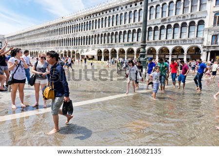 VENICE, ITALY - JULY 12 2014: The flooding of St Mark\'s Square and tourists on June 16, 2014 in Venice, Italy. More then 46 mln tourists is expected to visit Italy in year 2014.