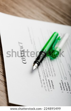 Pen and contract papers on wooden desk