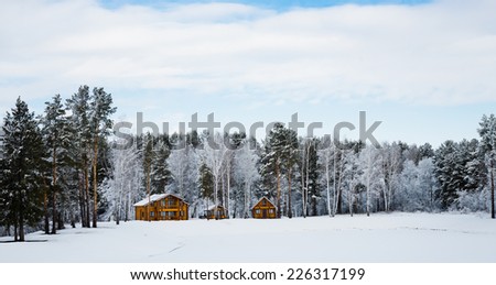 Wooden houses in a nature area covered with freshly fallen snow.