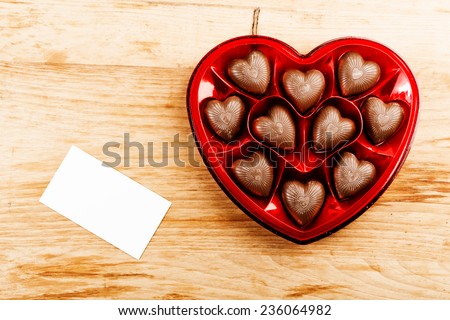 chocolate pralines in red heart shape box on table