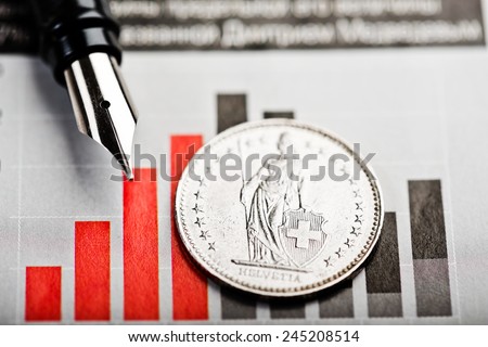 One Swiss Franc coin on fluctuating graph. Rate of the Swiss Franc (shallow DOF)