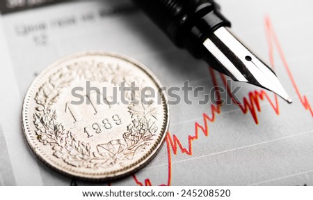 One Swiss Franc coin on fluctuating graph. Rate of the Swiss Franc (shallow DOF)