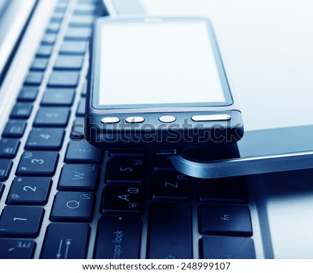 two phones and tablet pc on laptop