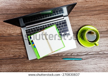 Office desk with laptop computer, planner, cup of tea