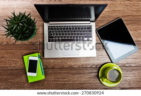 Office desk with laptop computer, tablet pc, planner, pen, mobile smartphone and cup of tea.
