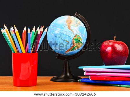 Globe, notebook stack and pencils.