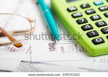 Business work station with paperwork income tax return, calculator and pen