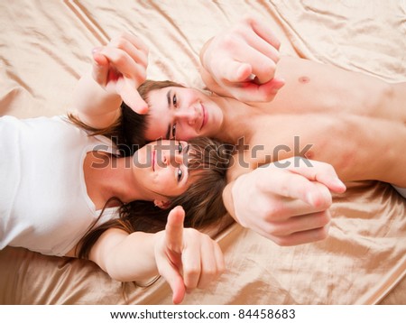 wide angle picture of a young couple pointing to you
