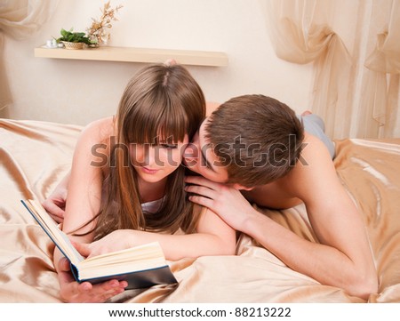 A boy trying to get some attention from his girlfriend, who\'s busy reading a book.