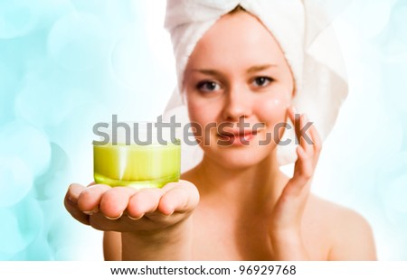beautiful woman in towel applying cream after bath with lights in the background