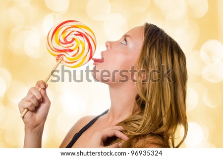 Woman licking sweet sugar candy closeup with lights in the background