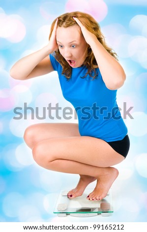 A young girl screams as she sees her weight on the scale with blue lights in the background