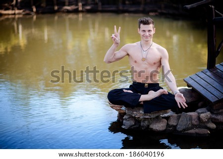 Outdoor yoga session in beautiful garden with a lake - young man funny portrait