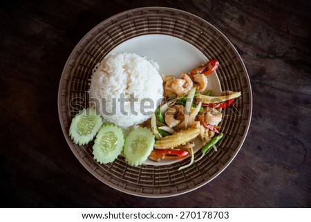 Stir fried prawns, red hot chilli pepper, babycorn, onion, bean served with cucumber and rice. Traditional thai cuisine.