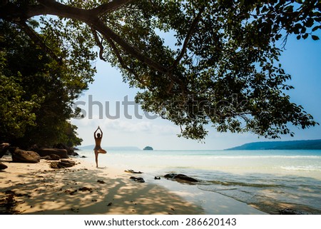 Summer yoga session on a beach - tropical Koh Rong island, Cambodia. Vriksha-asana - tree pose.