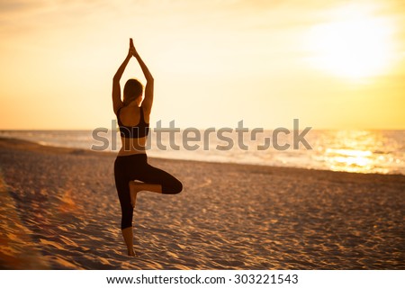 Summer yoga session on a beautiful golden beach - polish Grzybowo village, near to Kolobrzeg. Vriksha-asana - tree pose.