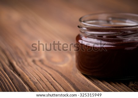 Homemade DIY natural chocolate jam made of plums, cacao powder and vanilla. Healthy marmalade in glass jar on a wooden table