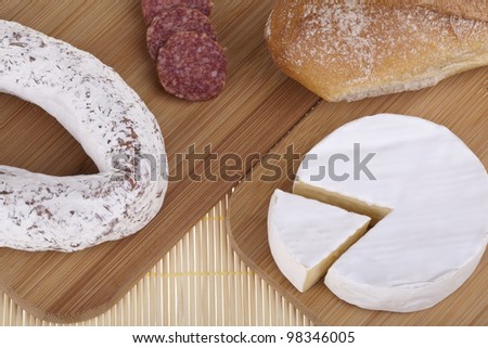 Tasty camembert cheese and salami sausage with bread on a wooden desk. Studio photo on white background