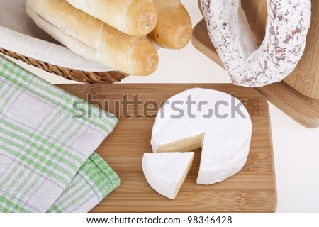 Tasty camembert cheese and salami sausage with bread on a wooden desk. Studio photo on white background