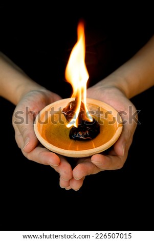 hands holding indian religion oil lamp. Clay with oil & fire flame burning represent faith, blessing, happiness of asian hindu people. Deepavali or diwali festival celebration. Culture of Indian