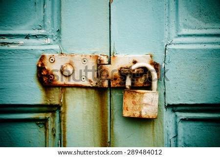 Rusty padlock on old painted wooden door