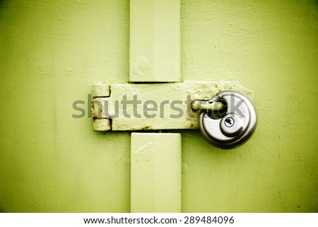 Rusty padlock on old green painted wooden door