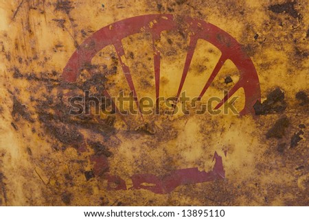 Damaged and worn shell company logo faded and scratched on yellow oil drum