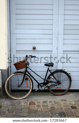Bicycle with basket leaning against light blue door, Lille, France