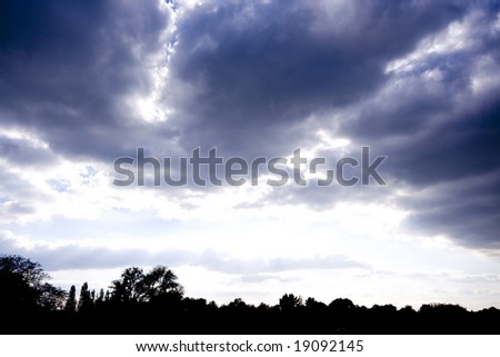 Stormy cloudscape over London with silhouette of trees below, Regents Park, London, England UK