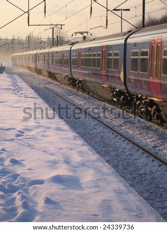Train speeding past snow covered station, London England UK
