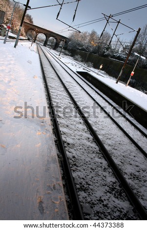 Snow covered train platform with bridge in distance
