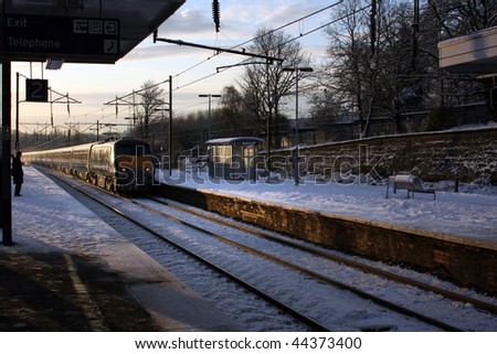 Snow covered train platform early morning with train speeding past