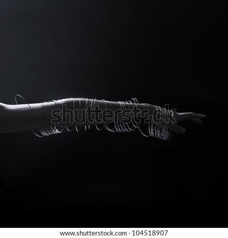 The arm with the wire around on the black background
