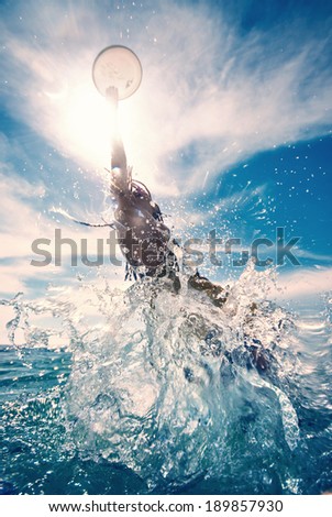 young man jumping in the water, summer beach activity, frisbee
